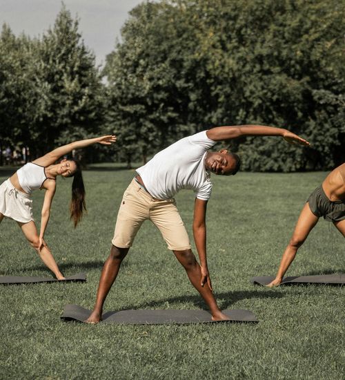 Diverse group of people practicing yoga outdoors.